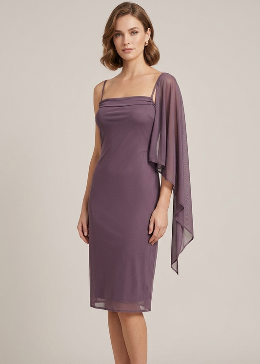 A woman models a knee-length mauve dress with a draped chiffon capelet over one shoulder, paired with nude high-heeled sandals, against a solid light beige studio background.