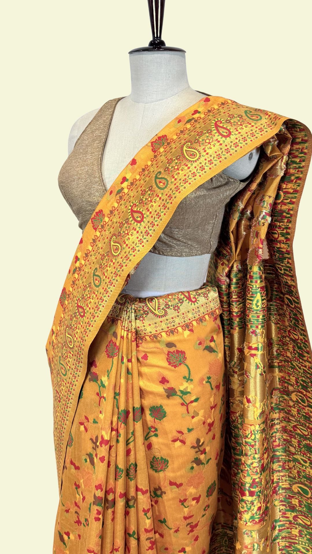 Orange saree with floral patterns on a mannequin against a beige background